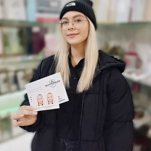 Девушка держит в руке фотографии на документы